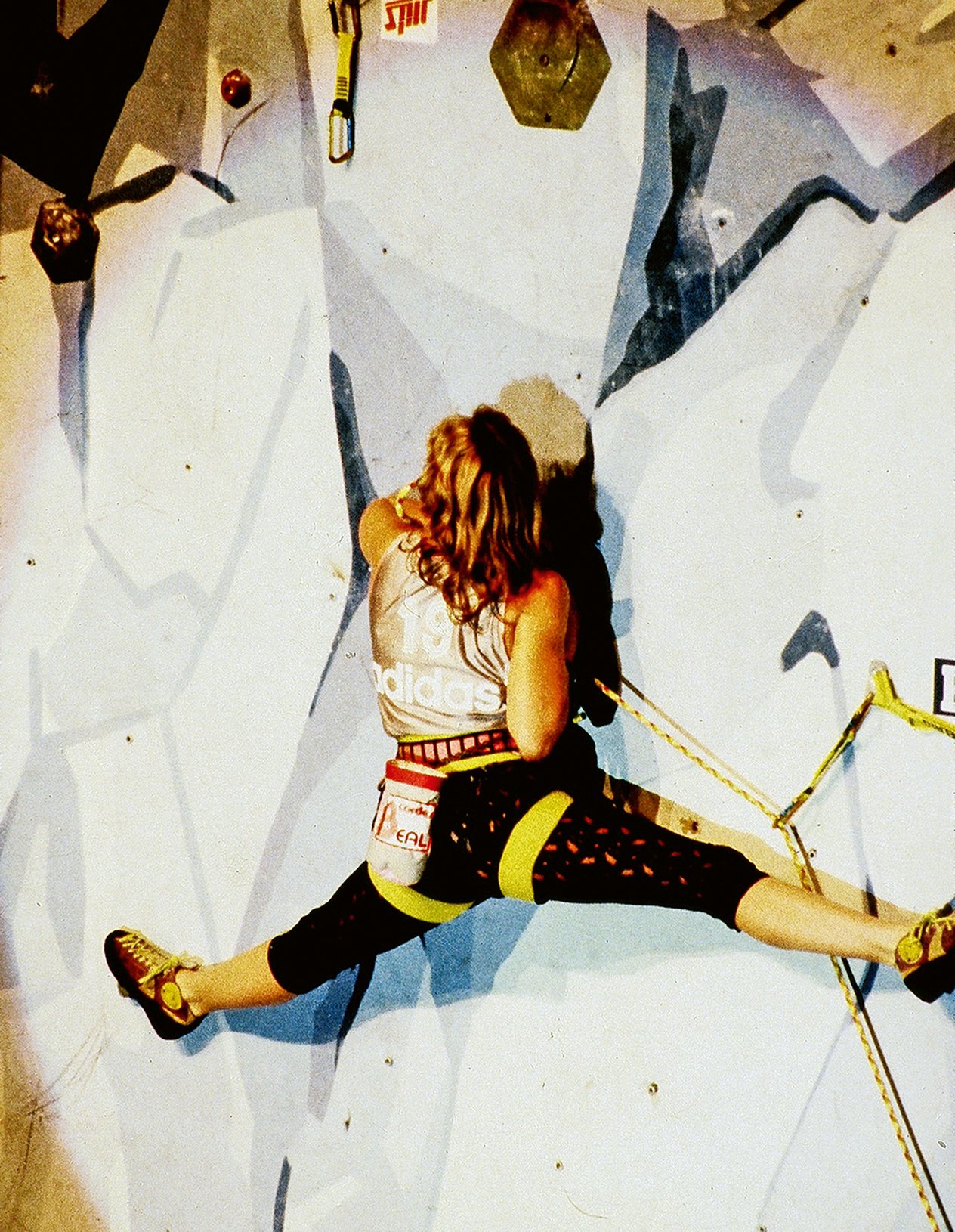 Climber fa una spaccata su una parete artificiale