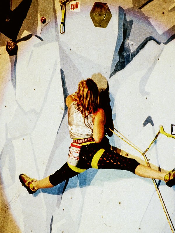 Climber fa una spaccata su una parete artificiale