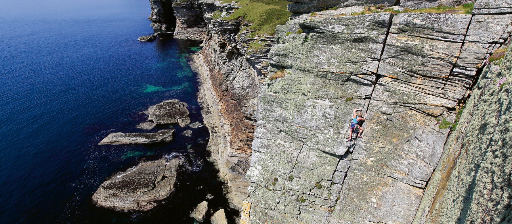 Climber in parete a picco sul mare