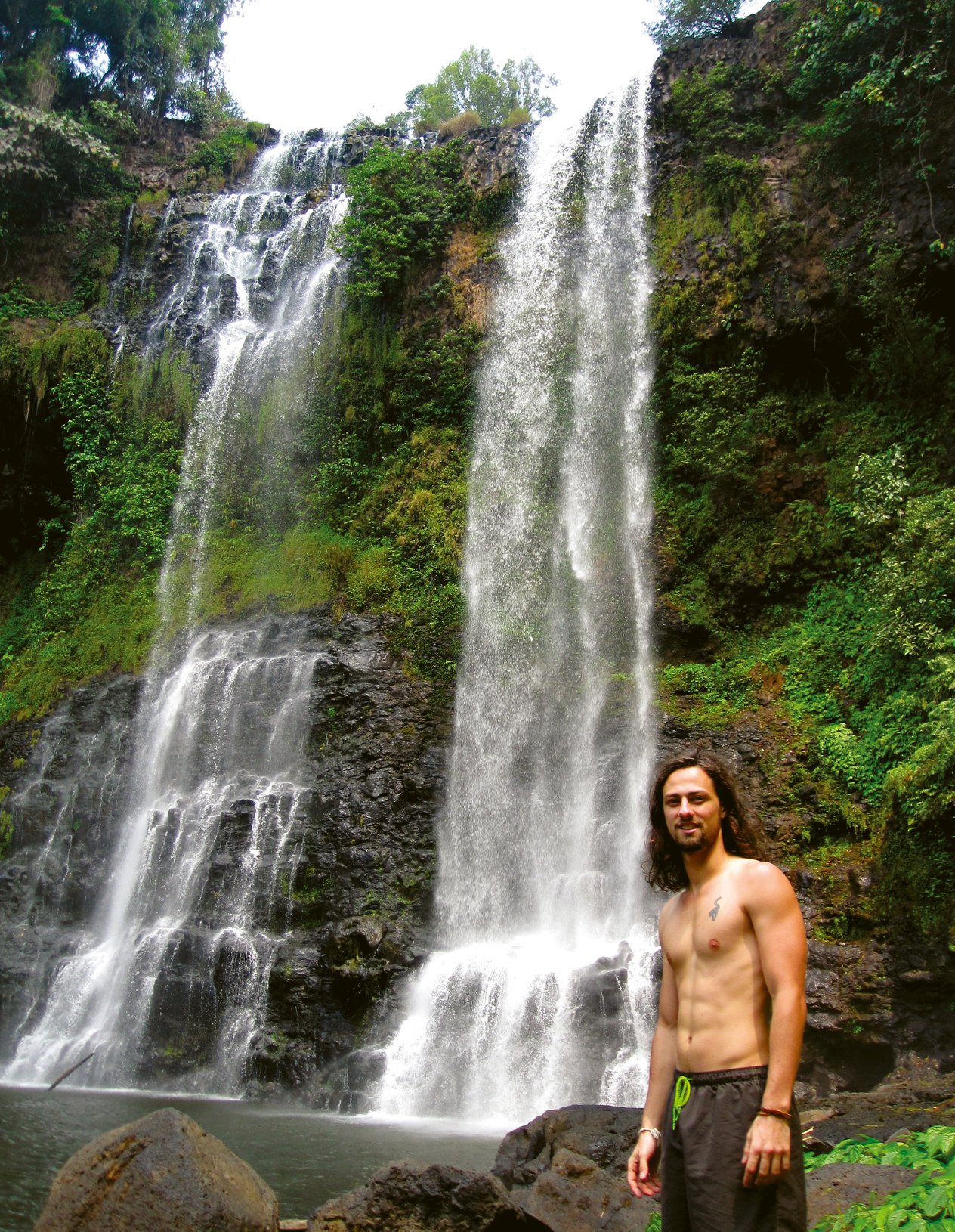 ragazzo in Asia posa davanti a una cascata
