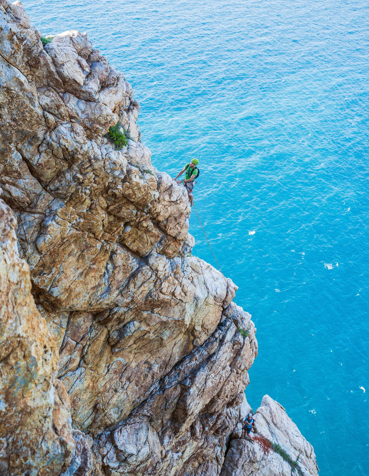Climber in parete a picco sul mare