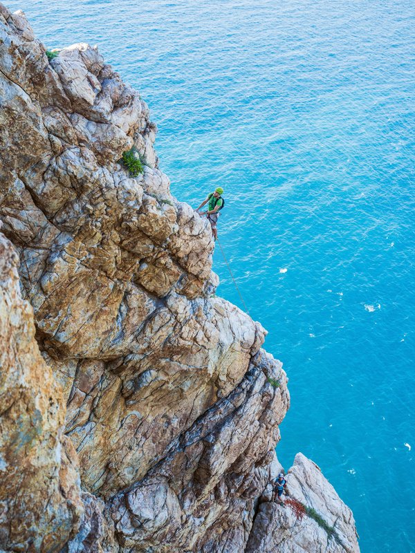 Climber in parete a picco sul mare