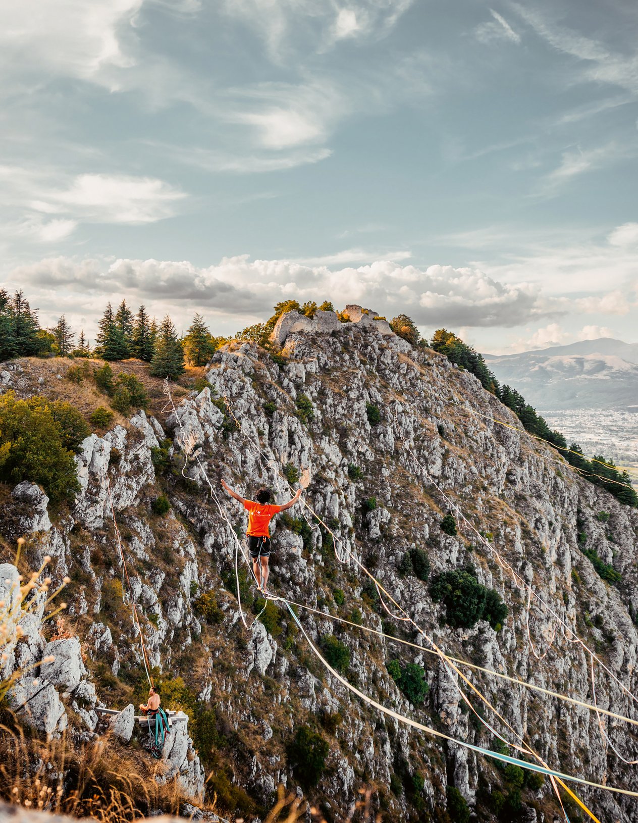 ragazzo su una linea di slackline tirata tra due montagne